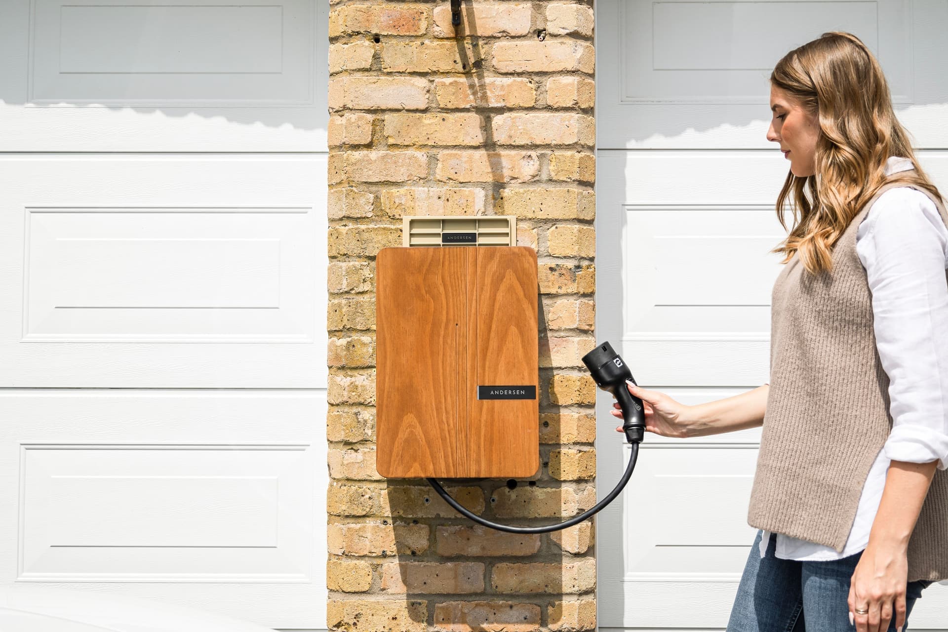 An electric car charging from a wall-mounted Level 2 charger in a home garage