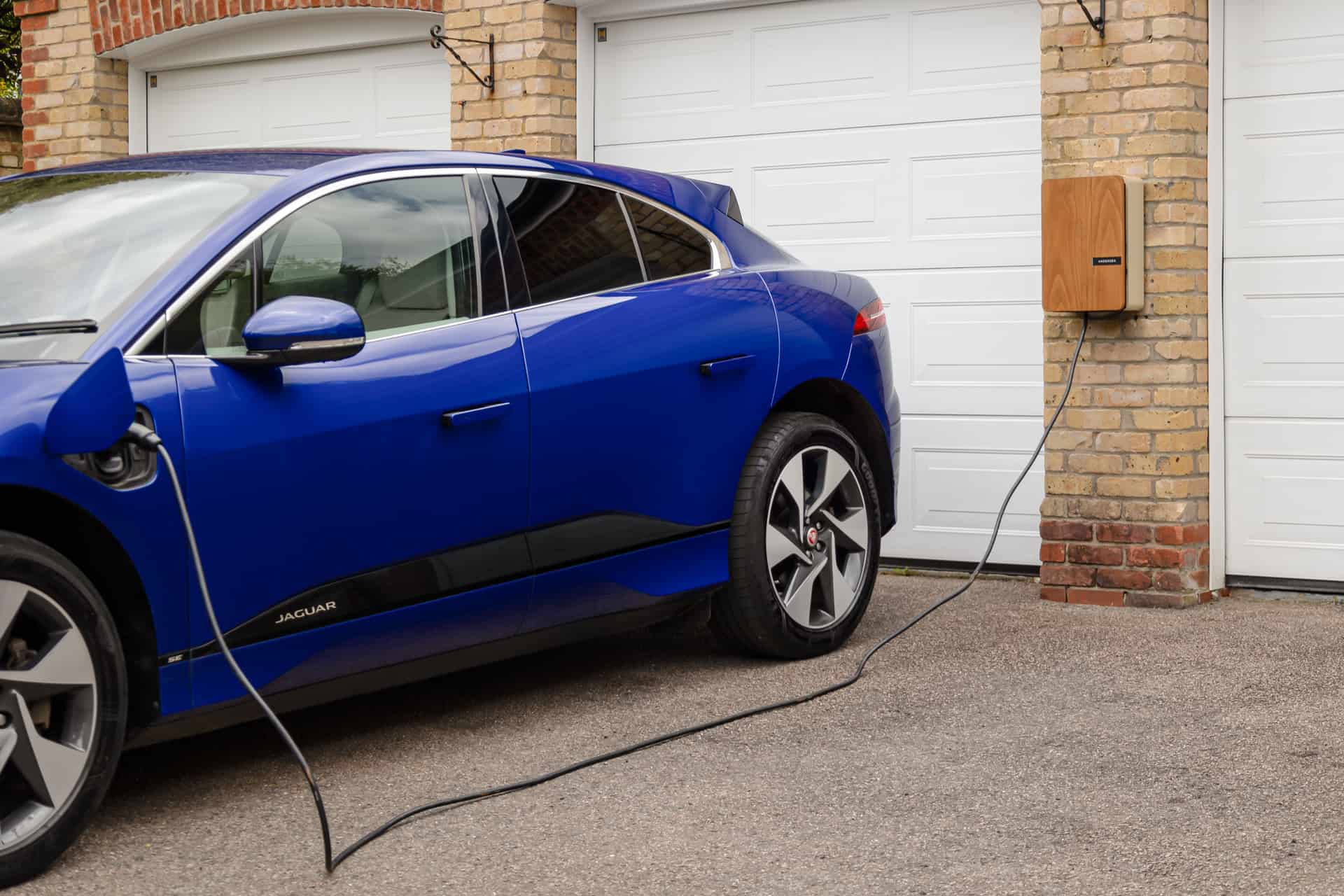 An electric car charging in a driveway in the evening
